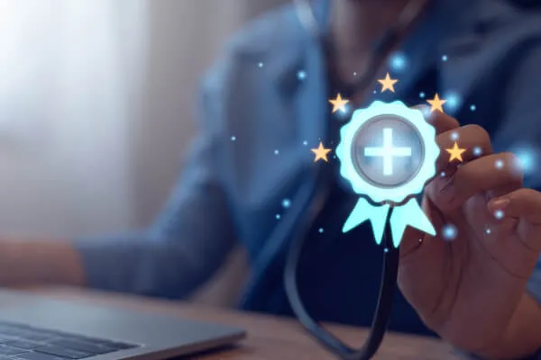 Woman sitting behind laptop holding a badge in her hand